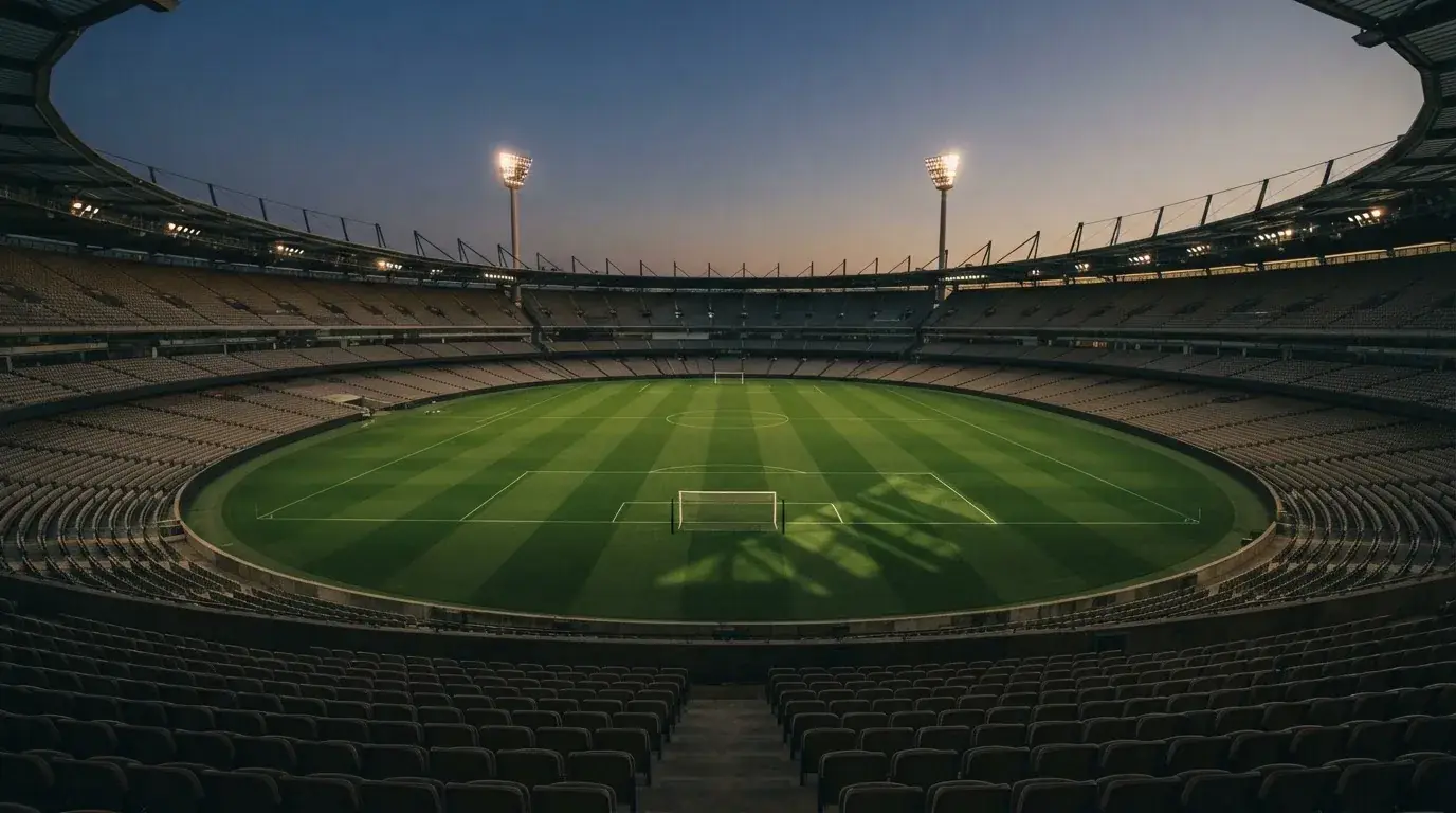 Een leeg voetbalstadion met lichtmasten bij schemering
