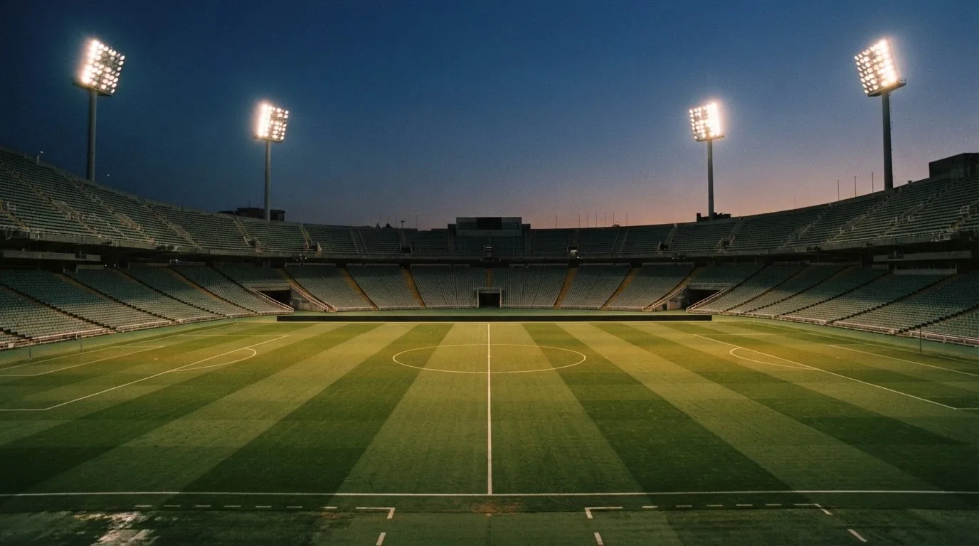 Een leeg voetbalstadion met lichtmasten bij schemering