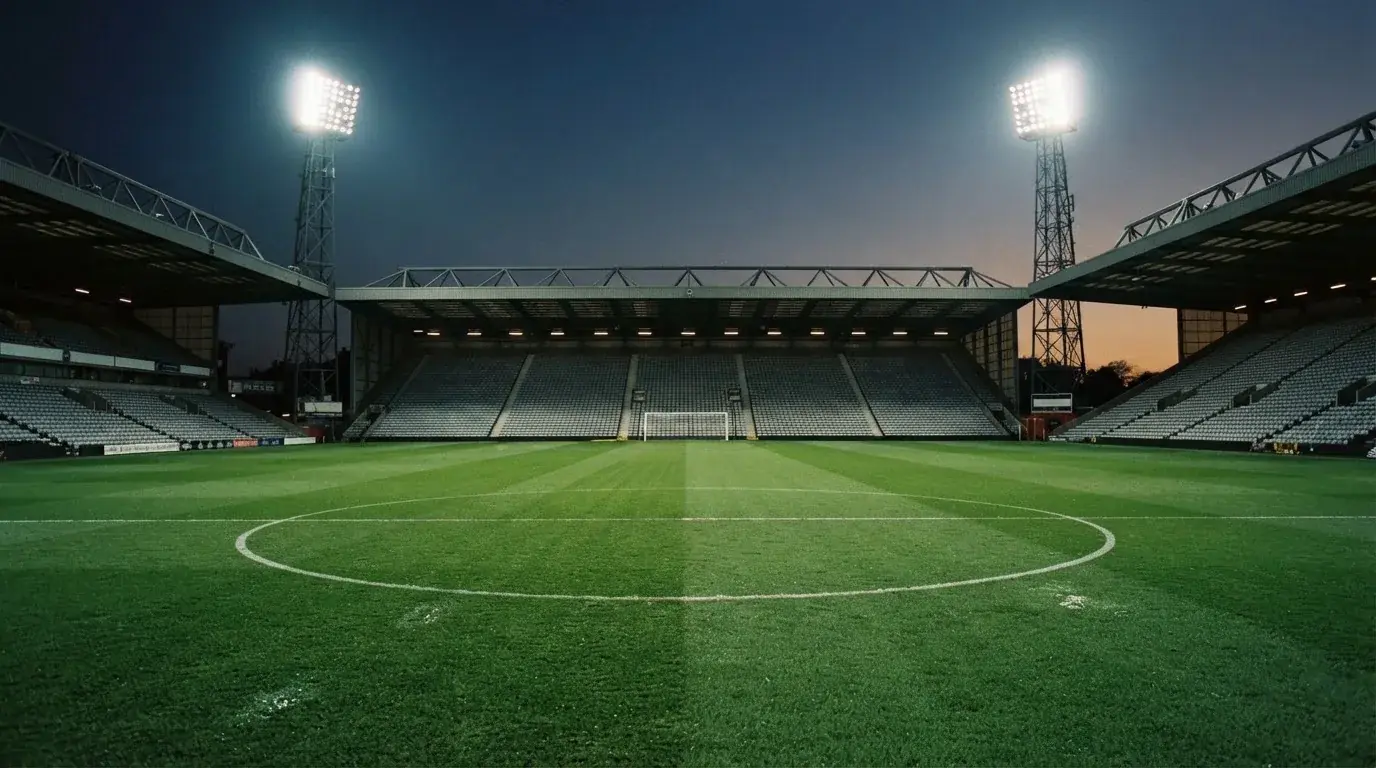 Een leeg voetbalstadion met lichtmasten bij schemering