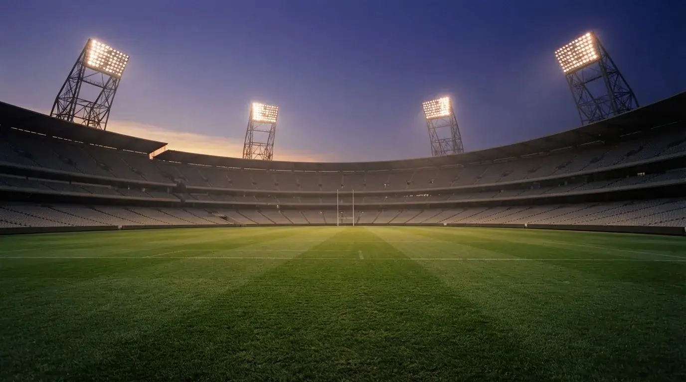 Een leeg voetbalstadion met lichtmasten bij schemering