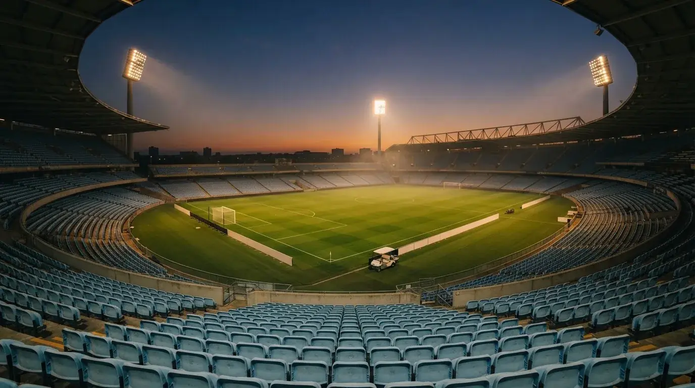 Een leeg voetbalstadion met lichtmasten bij schemering