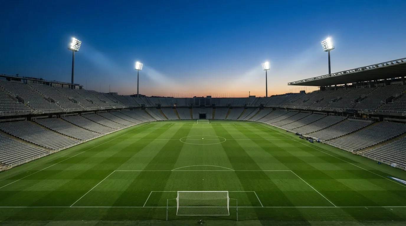 Een leeg voetbalstadion met lichtmasten bij schemering