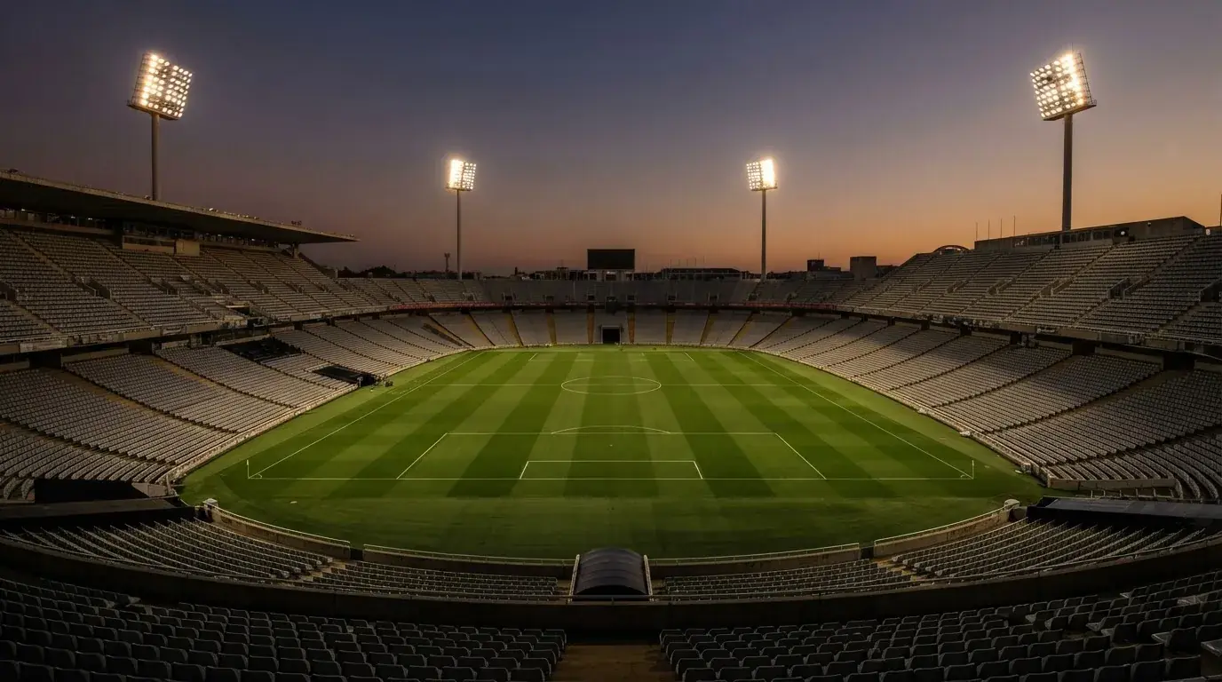 Een leeg voetbalstadion met lichtmasten bij schemering