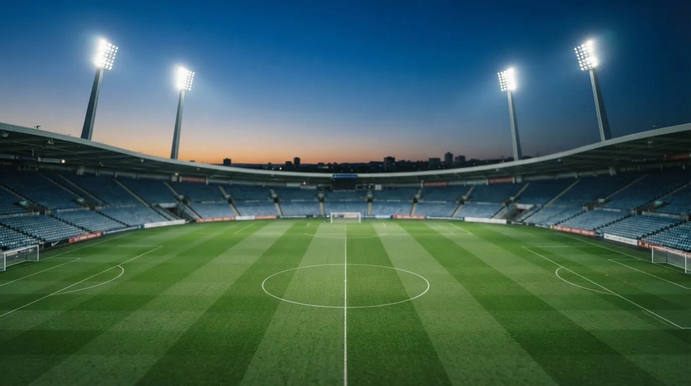 Een leeg voetbalstadion met lichtmasten bij schemering