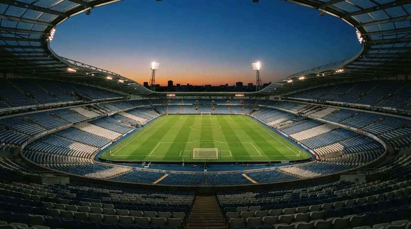 Een leeg voetbalstadion met lichtmasten bij schemering