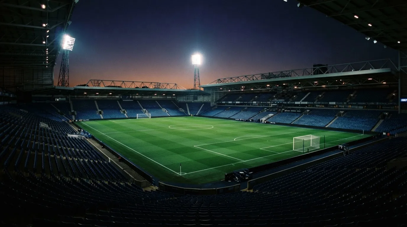 Een leeg voetbalstadion met lichtmasten bij schemering