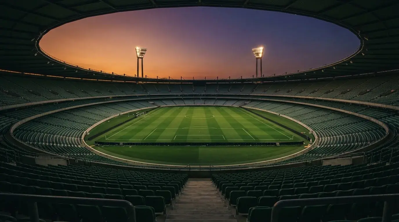 Een leeg voetbalstadion met lichtmasten bij schemering
