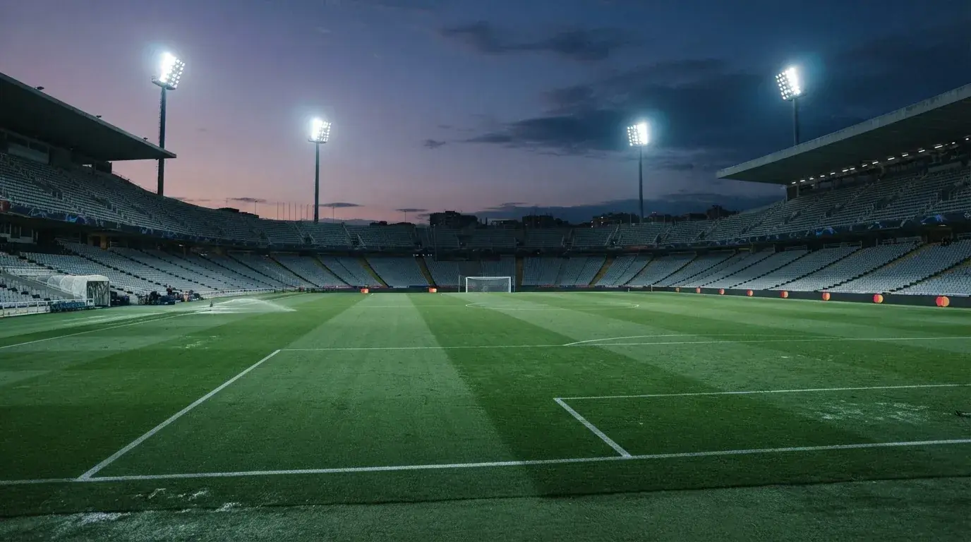 Een leeg voetbalstadion met lichtmasten bij schemering