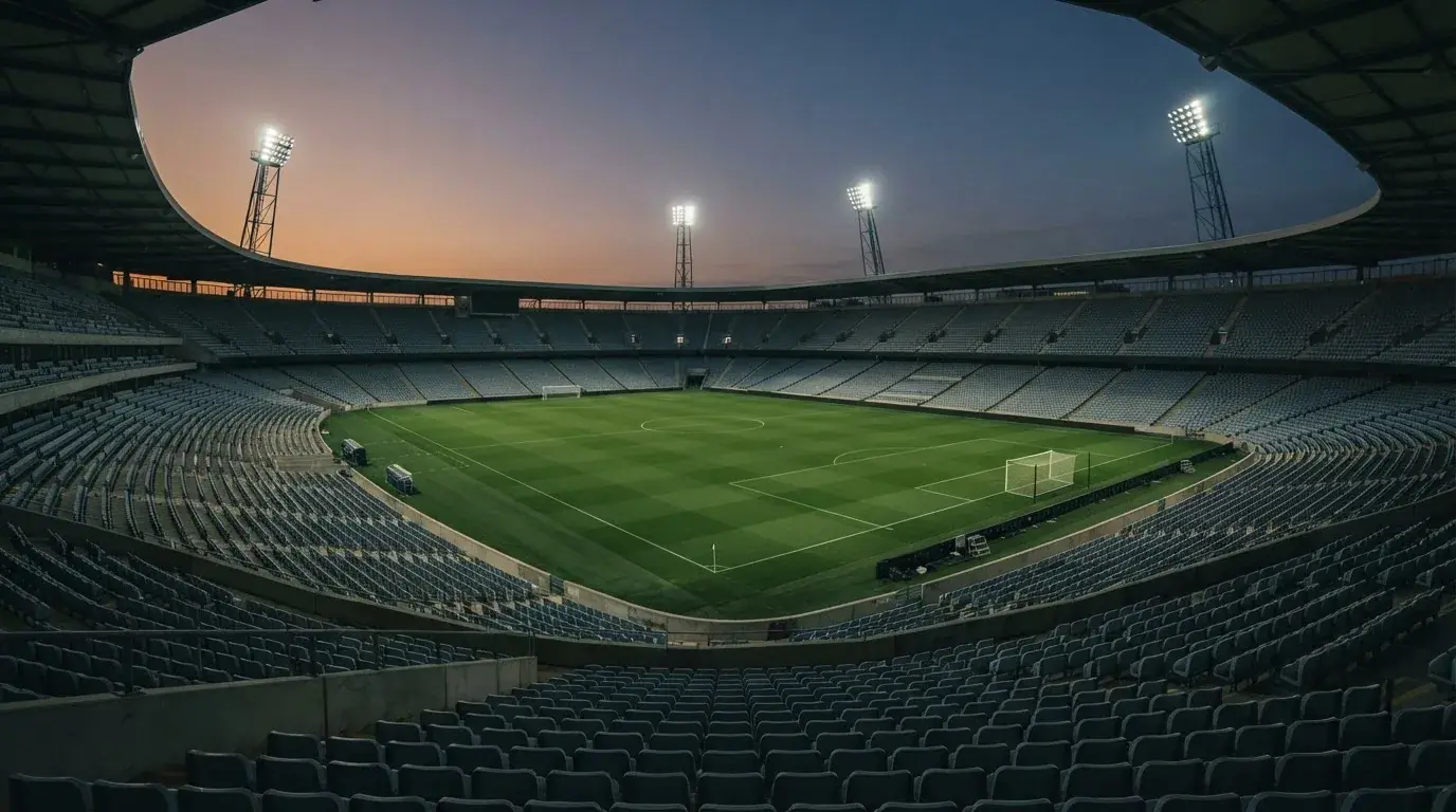 Een leeg voetbalstadion met lichtmasten bij schemering