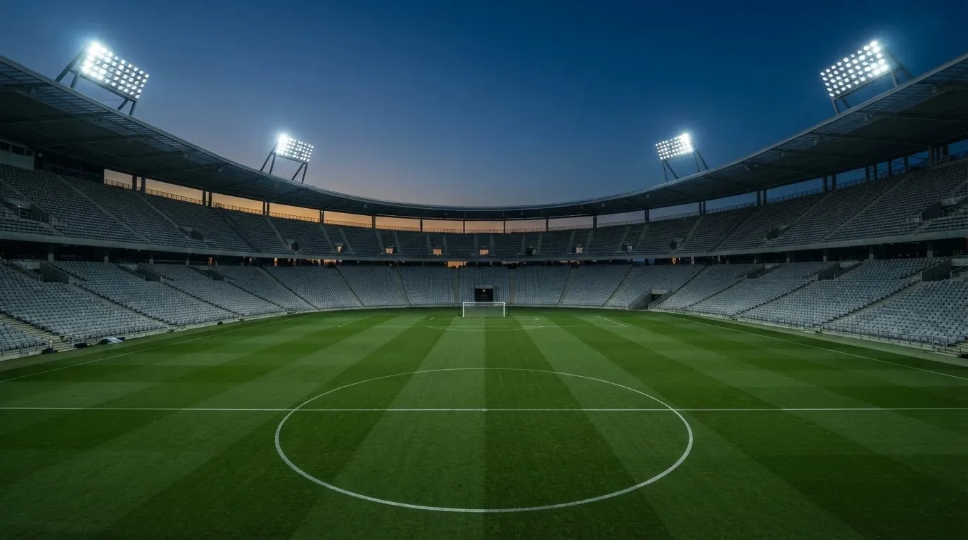 Een leeg voetbalstadion met lichtmasten bij schemering