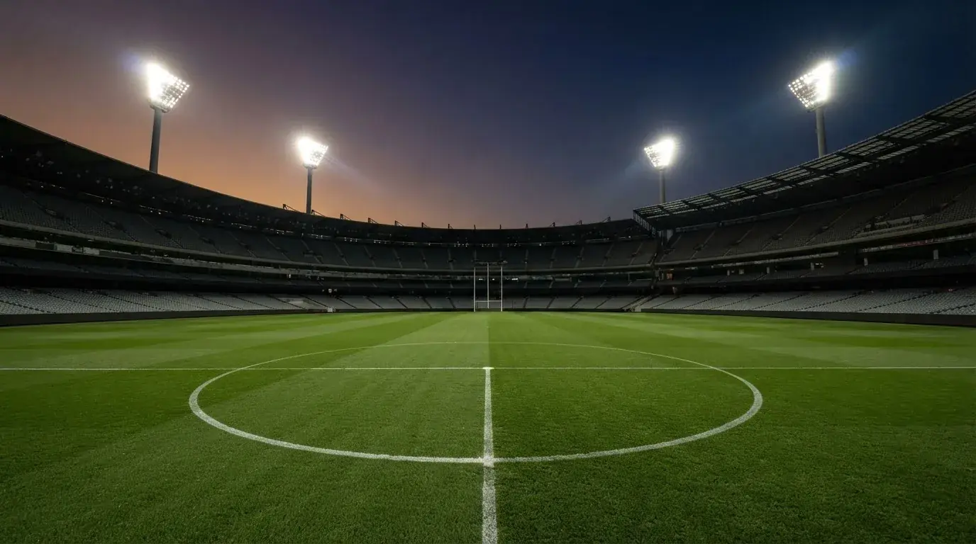 Een leeg voetbalstadion met lichtmasten bij schemering