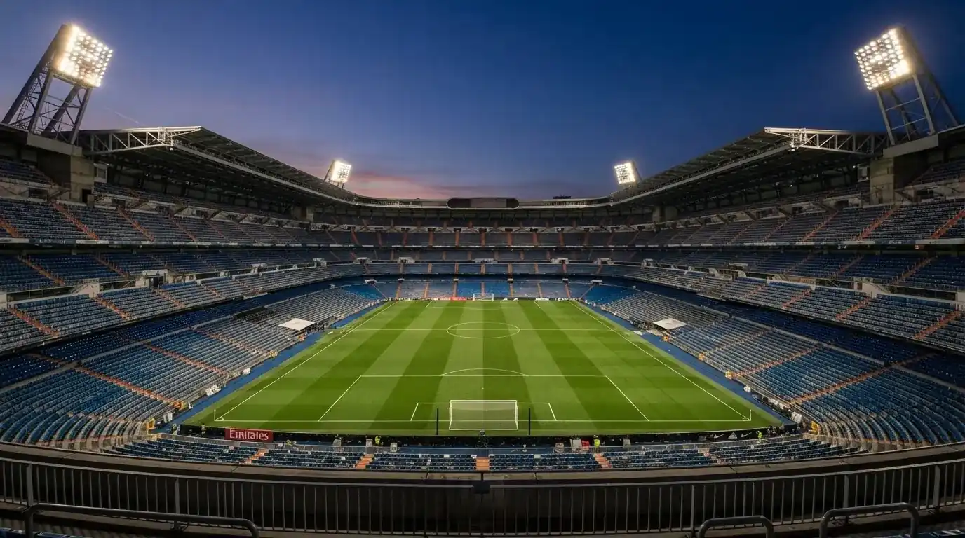 Een leeg voetbalstadion met lichtmasten bij schemering